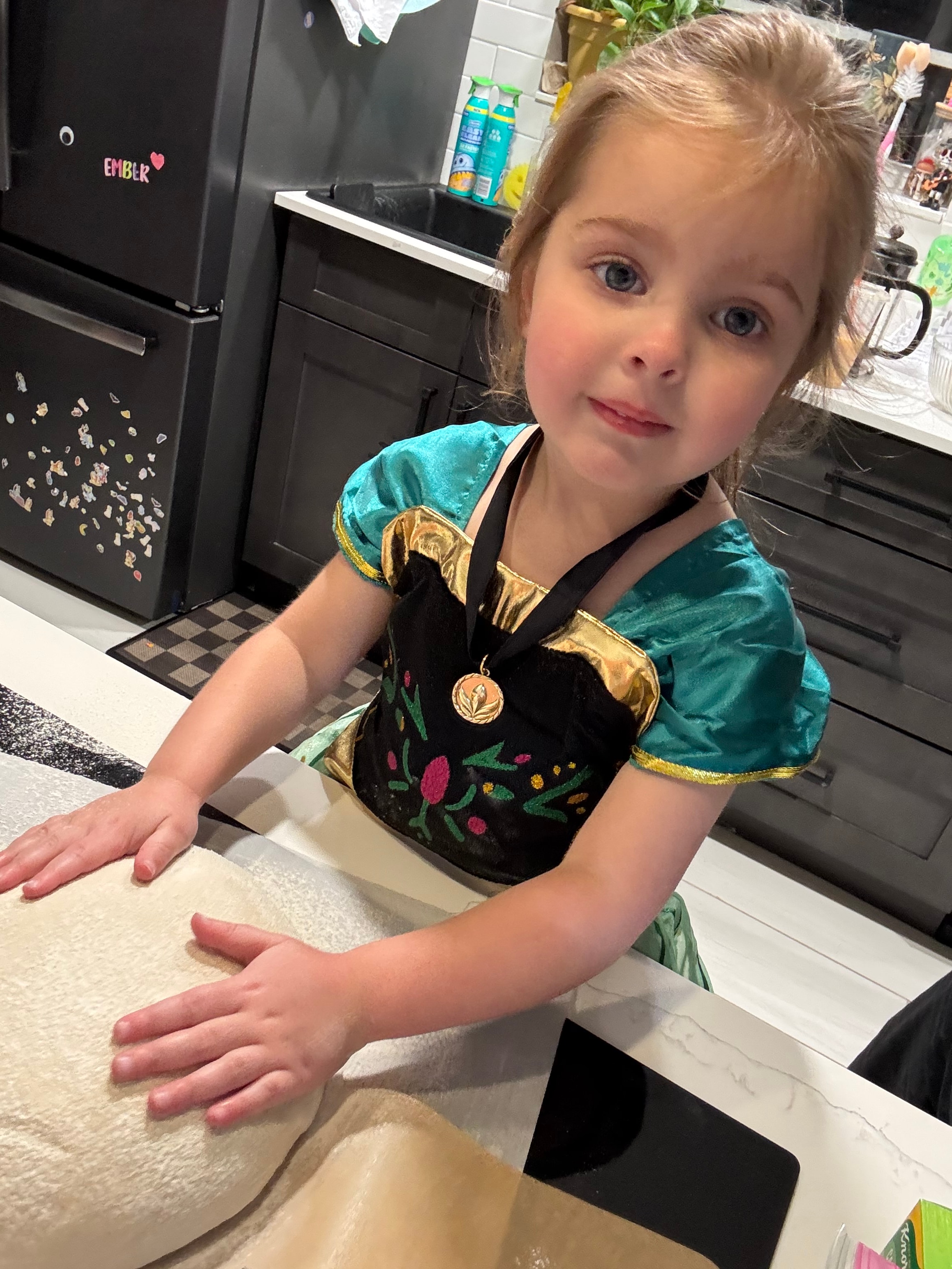Ember in her princess dress helping in the kitchen